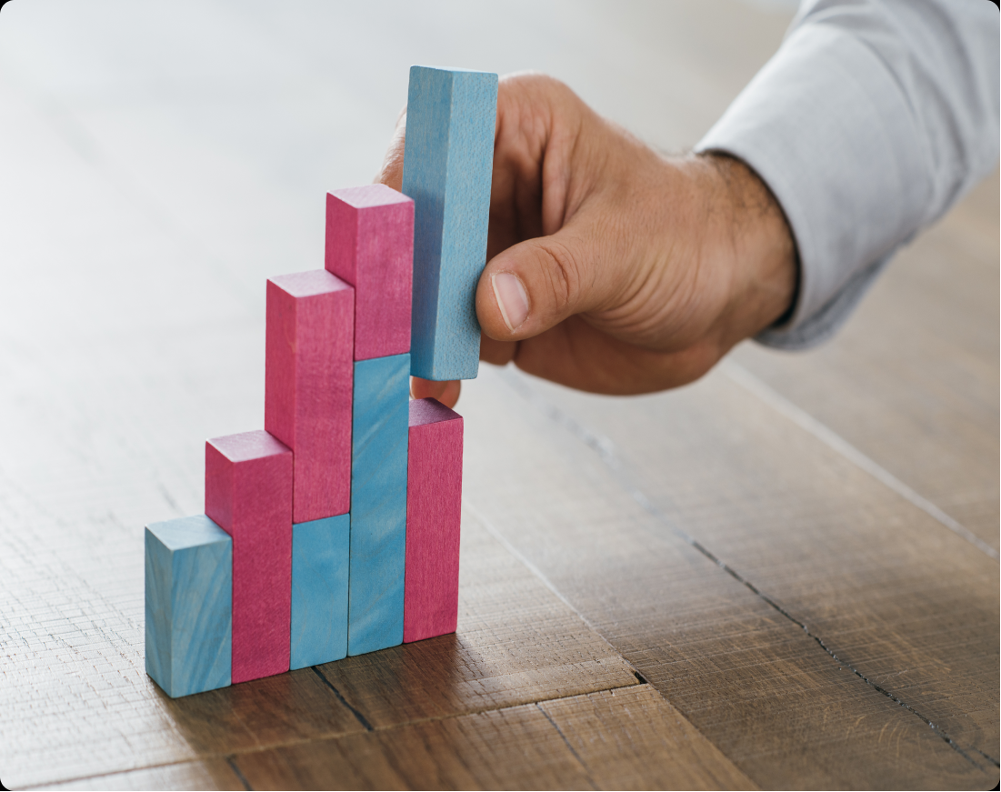 fundersfounders A closeup of a man's hand placing a block on top of a group of blocks that look like a financial graph