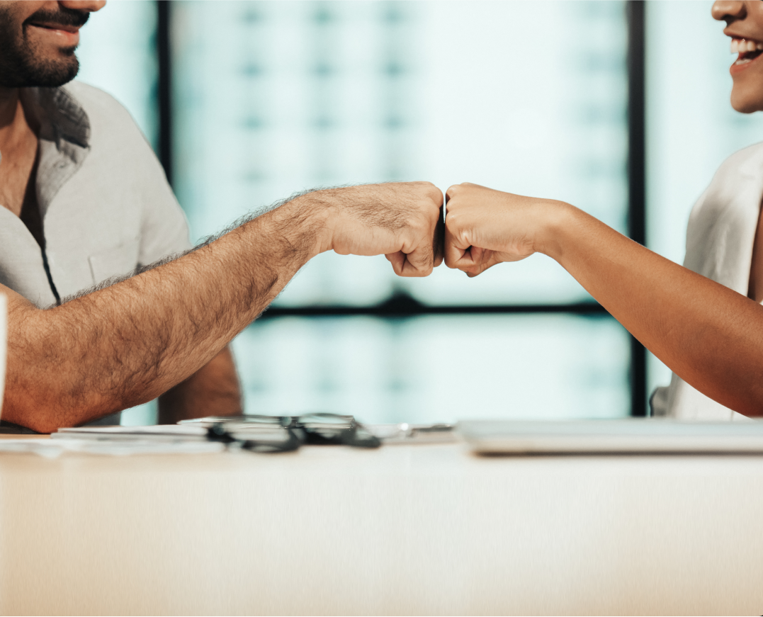 A man and a woman bump fists in a corporate setting