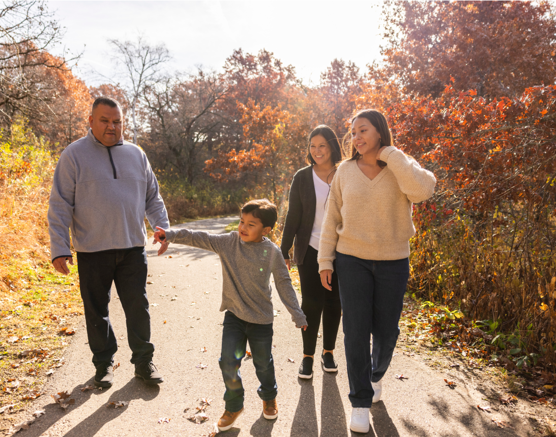 A family of four walks on a path through fall foliage.